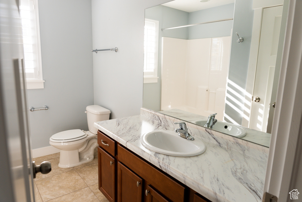 Bathroom with tile patterned flooring, vanity, toilet, and walk in shower