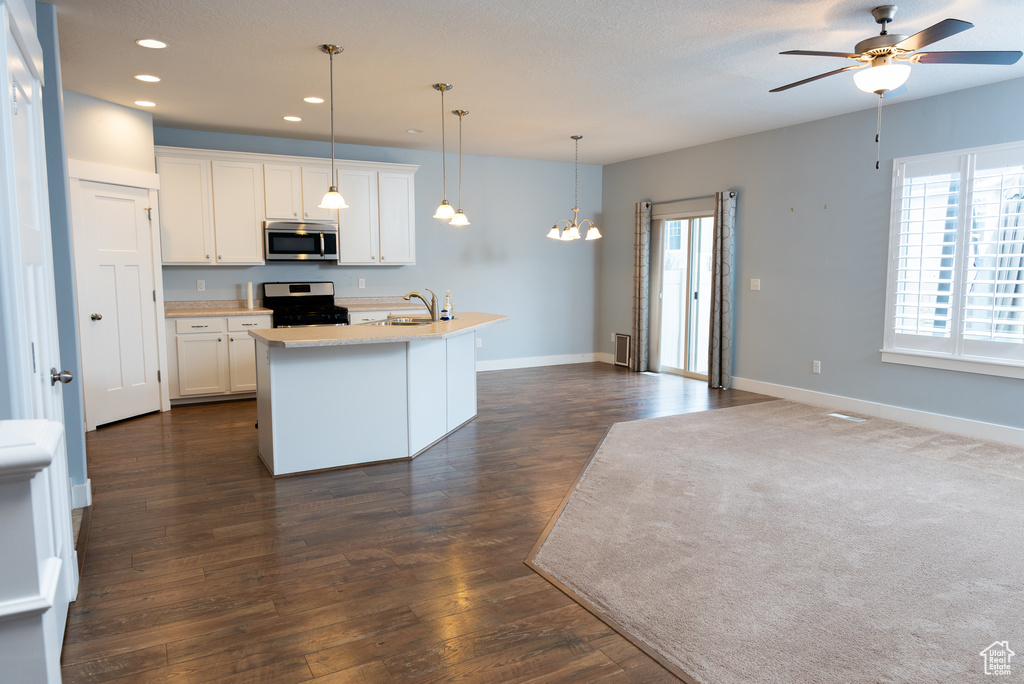 Kitchen featuring stainless steel appliances, pendant lighting, white cabinets, plenty of natural light, and an island with sink