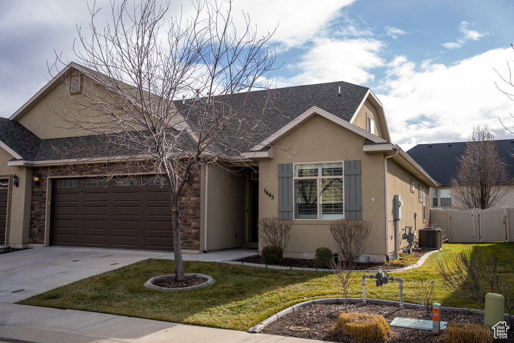 Ranch-style house with a front yard, a garage, and cooling unit