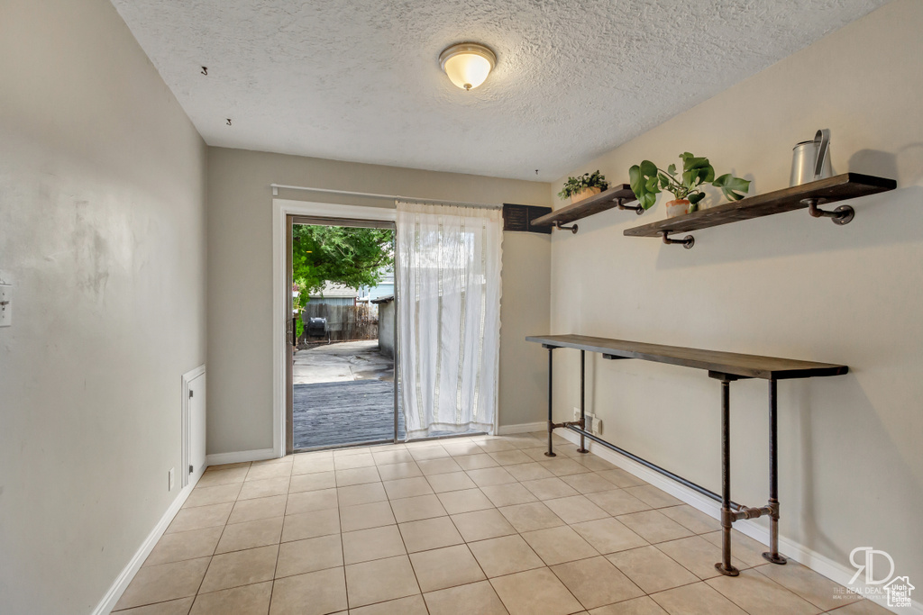 Entryway with a textured ceiling and light tile patterned flooring