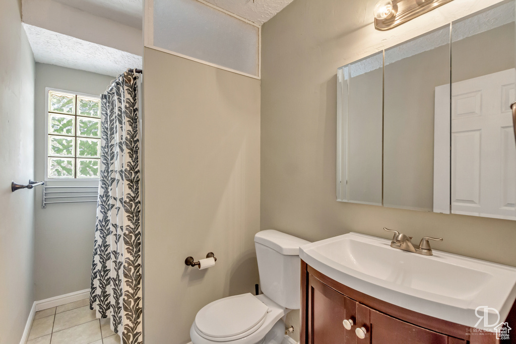 Bathroom with tile patterned flooring, vanity, a textured ceiling, and toilet