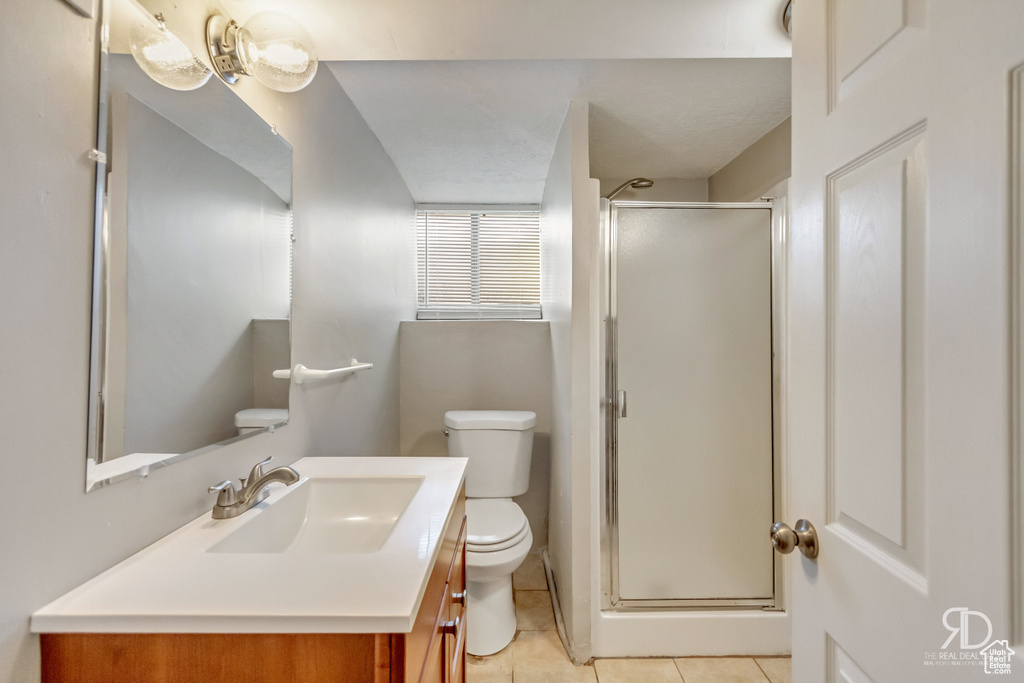 Bathroom featuring tile patterned floors, vanity, toilet, and an enclosed shower