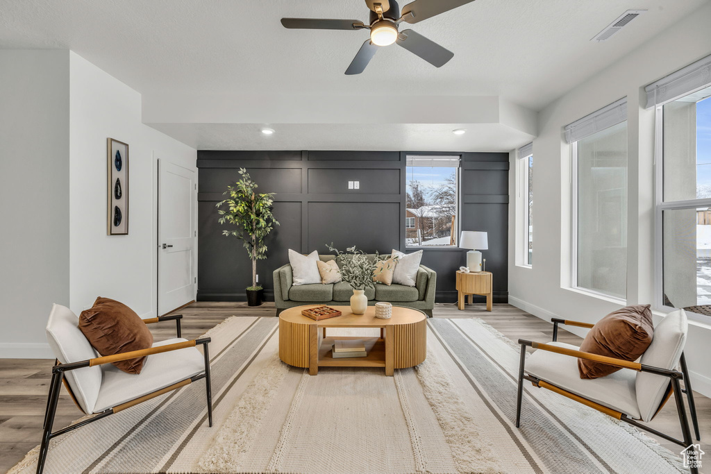 Living room with light wood-type flooring, visible vents, a decorative wall, and baseboards