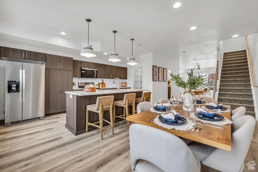 Dining area with light wood-style floors, stairway, and recessed lighting