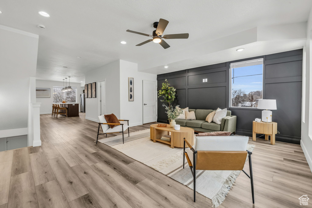Living area with light wood-style floors, plenty of natural light, and a decorative wall