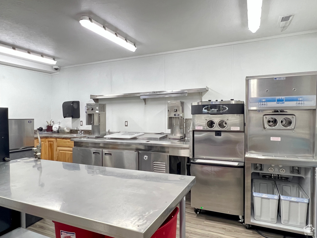 Kitchen with white cabinetry, stainless steel counters, and light hardwood / wood-style flooring