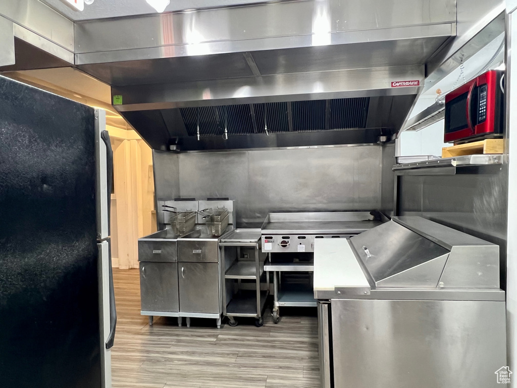 Kitchen featuring ventilation hood, wood-type flooring, and appliances with stainless steel finishes