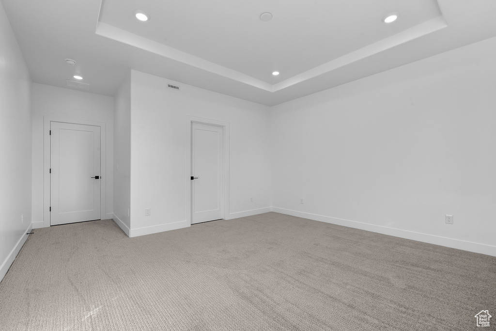 Carpeted empty room featuring a tray ceiling
