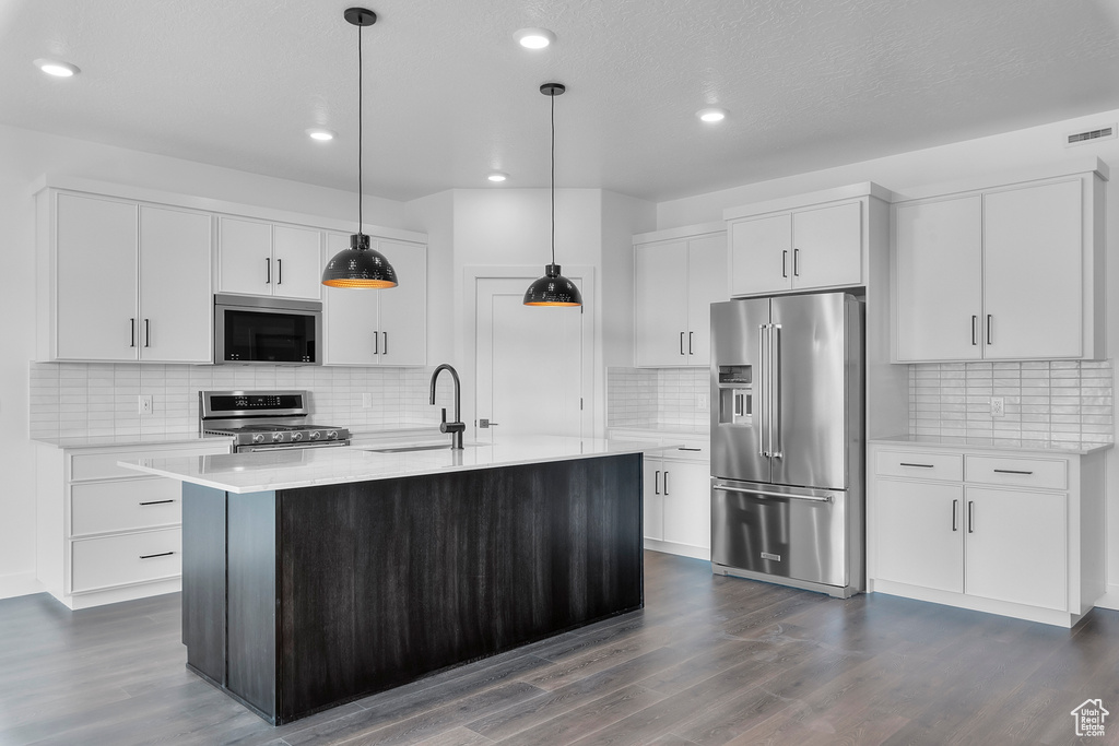 Kitchen featuring white cabinets, a kitchen island with sink, sink, and high quality appliances