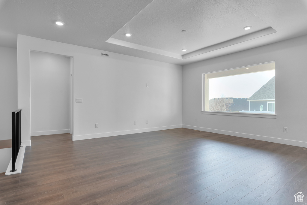 Unfurnished room featuring dark hardwood / wood-style floors and a tray ceiling