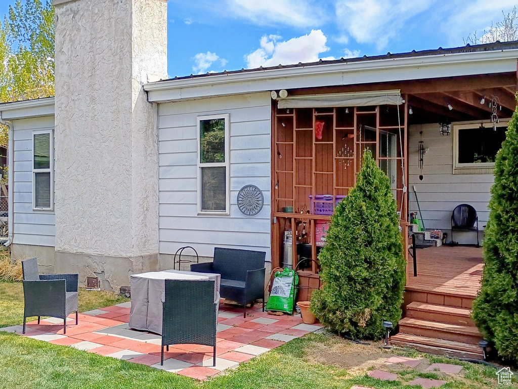 Back of property featuring a chimney, a patio, and a deck