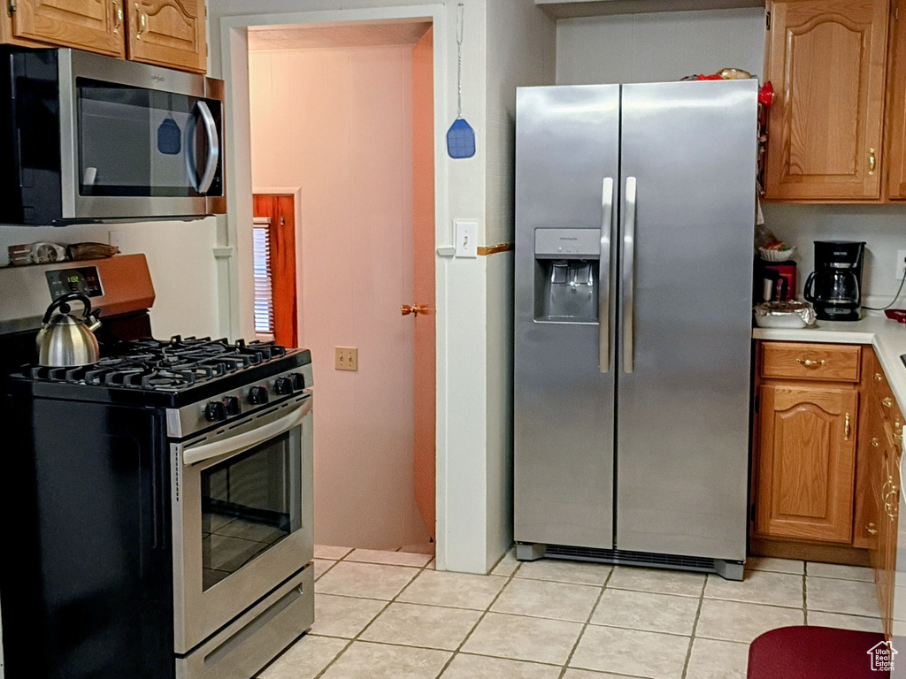 Kitchen with light tile patterned floors, brown cabinetry, visible vents, light countertops, and appliances with stainless steel finishes