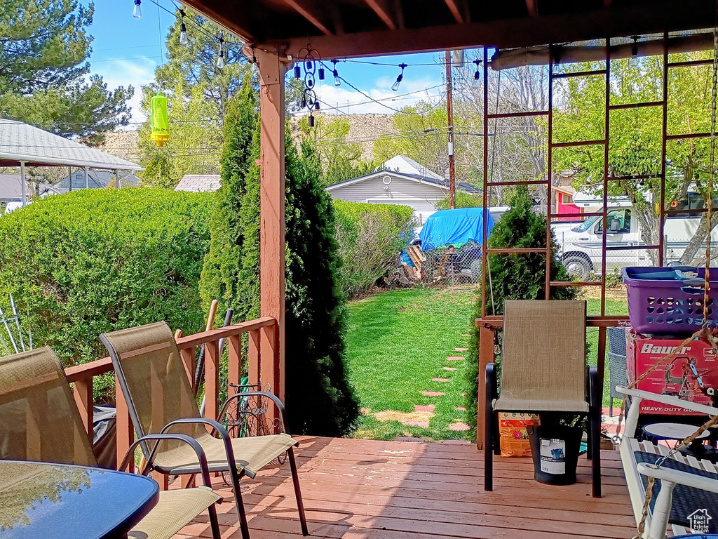 Wooden terrace featuring a lawn and fence