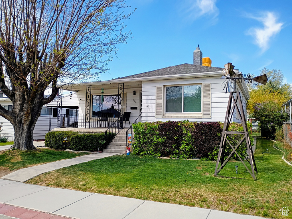 Bungalow-style house featuring a porch, a front yard, and a chimney