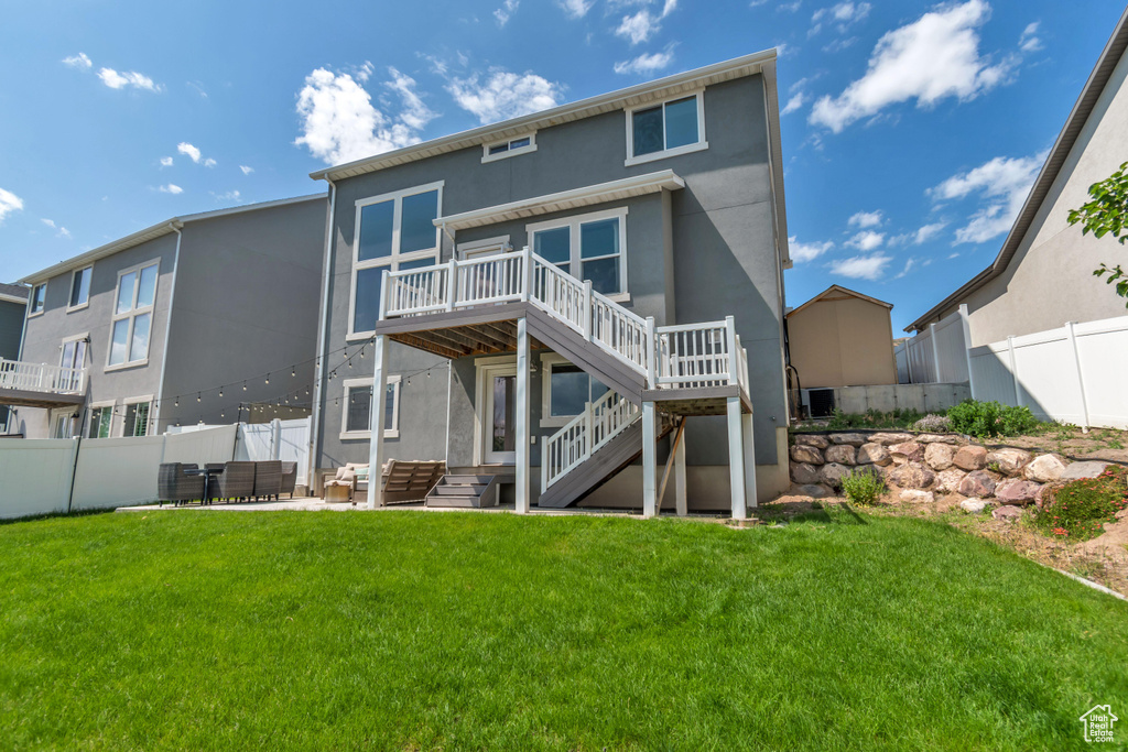 Back of property with stairway, stucco siding, a wooden deck, and a patio area