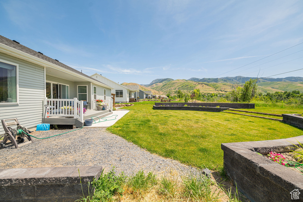 View of grassy yard featuring a deck with mountain view