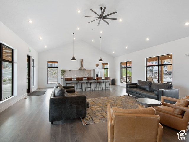 Living room with ceiling fan, a healthy amount of sunlight, dark wood-type flooring, and high vaulted ceiling