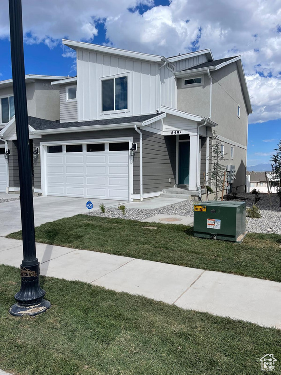 View of front facade featuring central AC unit, a garage, and a front lawn