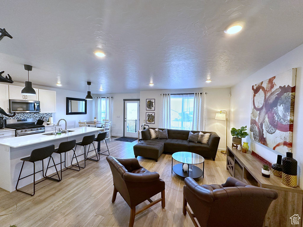 Living room with a textured ceiling, sink, and light hardwood / wood-style flooring