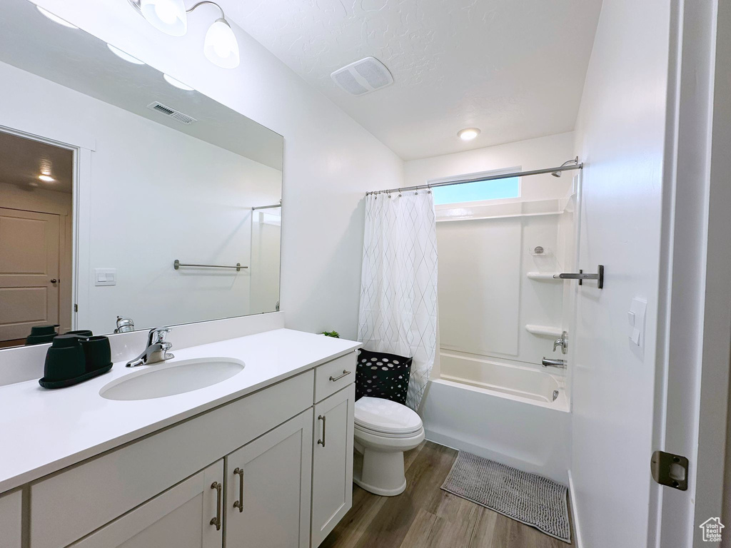 Full bathroom featuring hardwood / wood-style floors, vanity, shower / bath combo, and toilet