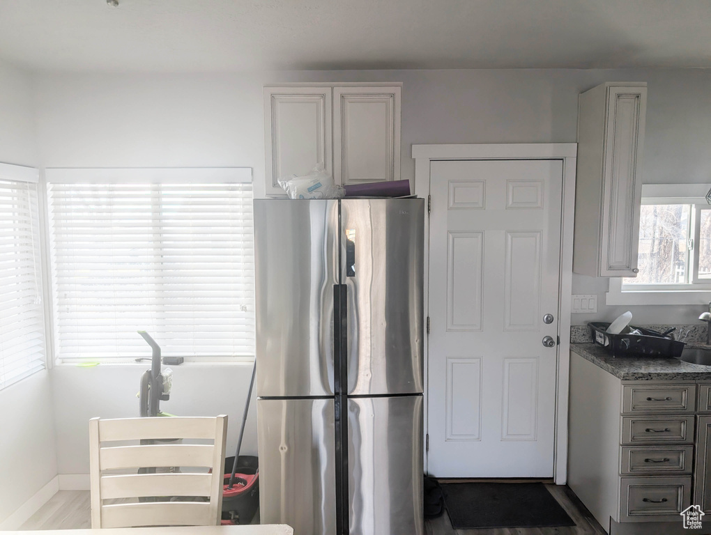 Kitchen featuring hardwood / wood-style floors, stainless steel fridge, and dark stone counters