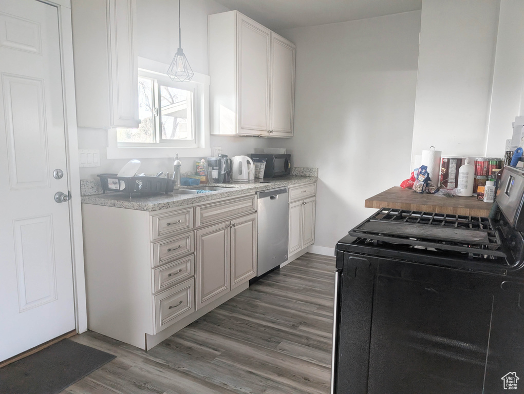 Kitchen featuring black appliances, white cabinets, hanging light fixtures, light stone countertops, and dark hardwood / wood-style flooring