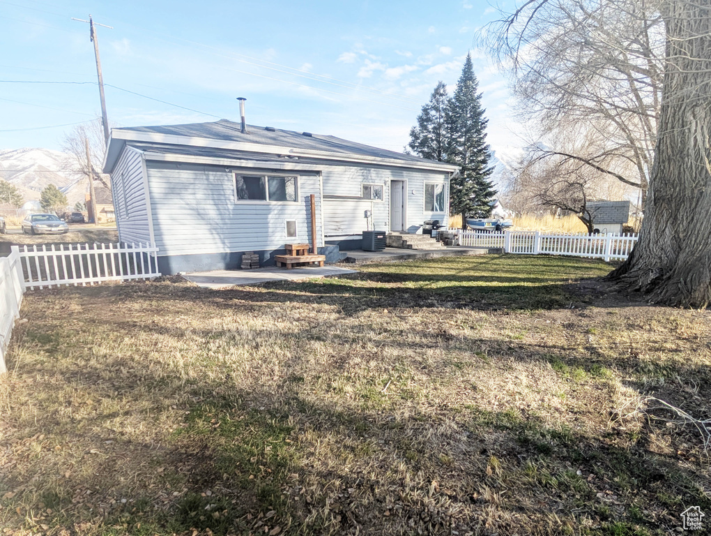 Rear view of property featuring central AC unit, a patio area, and a lawn
