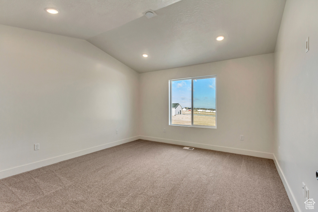 Carpeted spare room with lofted ceiling