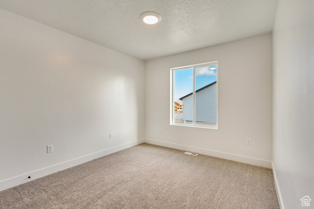 Carpeted spare room featuring a textured ceiling