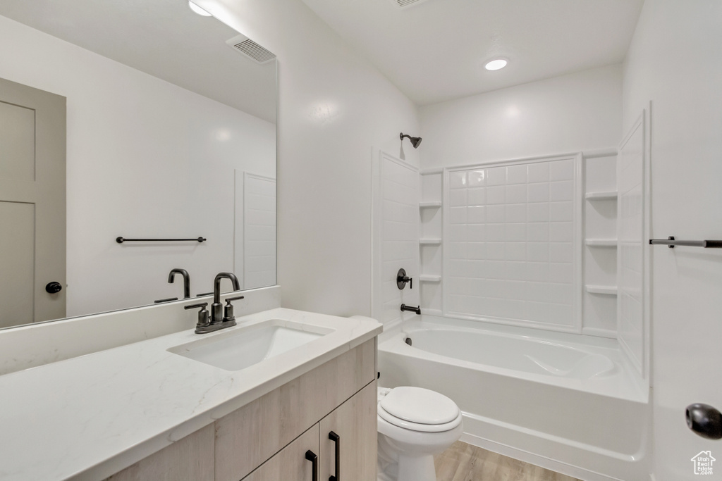 Full bathroom featuring hardwood / wood-style floors, vanity, toilet, and bathing tub / shower combination