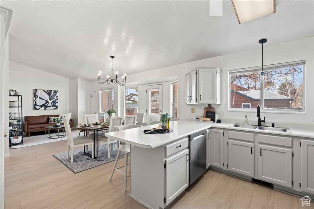 Kitchen featuring sink, stainless steel dishwasher, kitchen peninsula, a chandelier, and decorative light fixtures