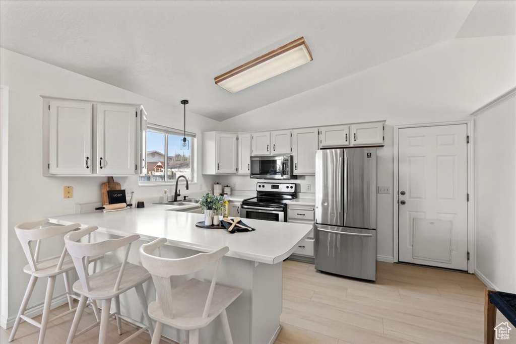 Kitchen with sink, kitchen peninsula, decorative light fixtures, white cabinetry, and stainless steel appliances