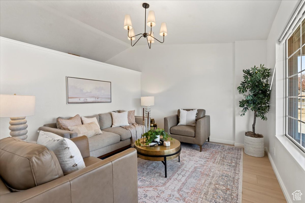 Living room featuring vaulted ceiling, a notable chandelier, and light wood-type flooring