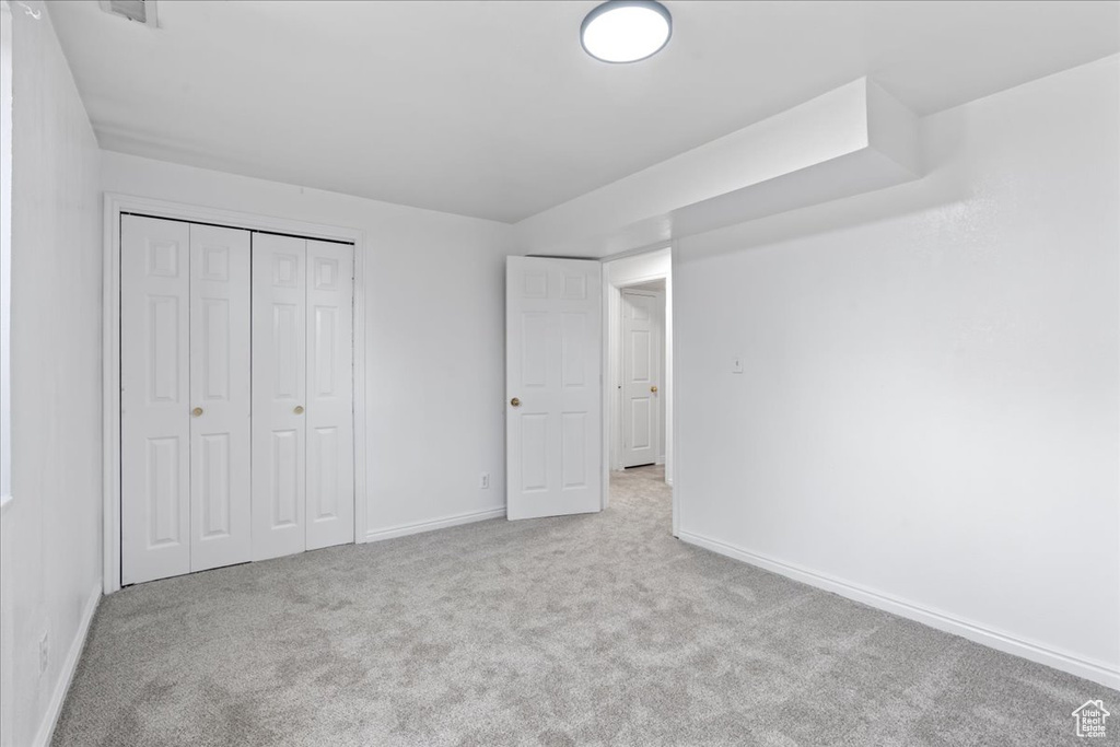 Unfurnished bedroom with light colored carpet and a closet