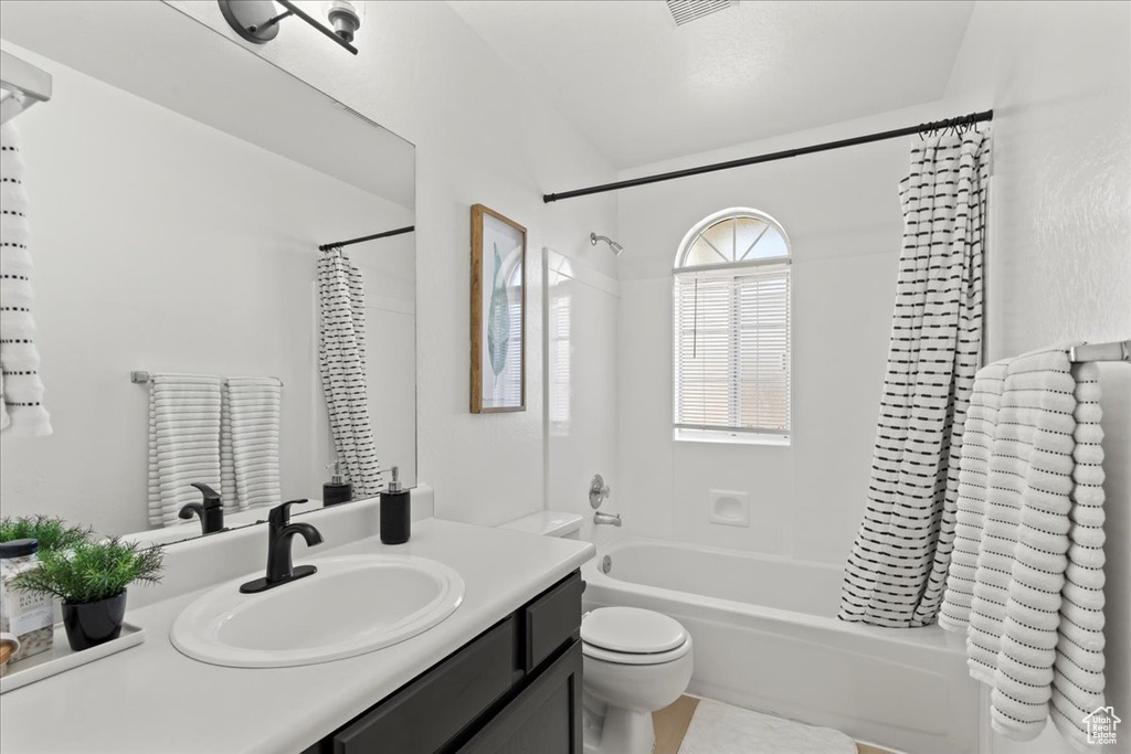 Full bathroom featuring vanity, shower / bath combo, and toilet