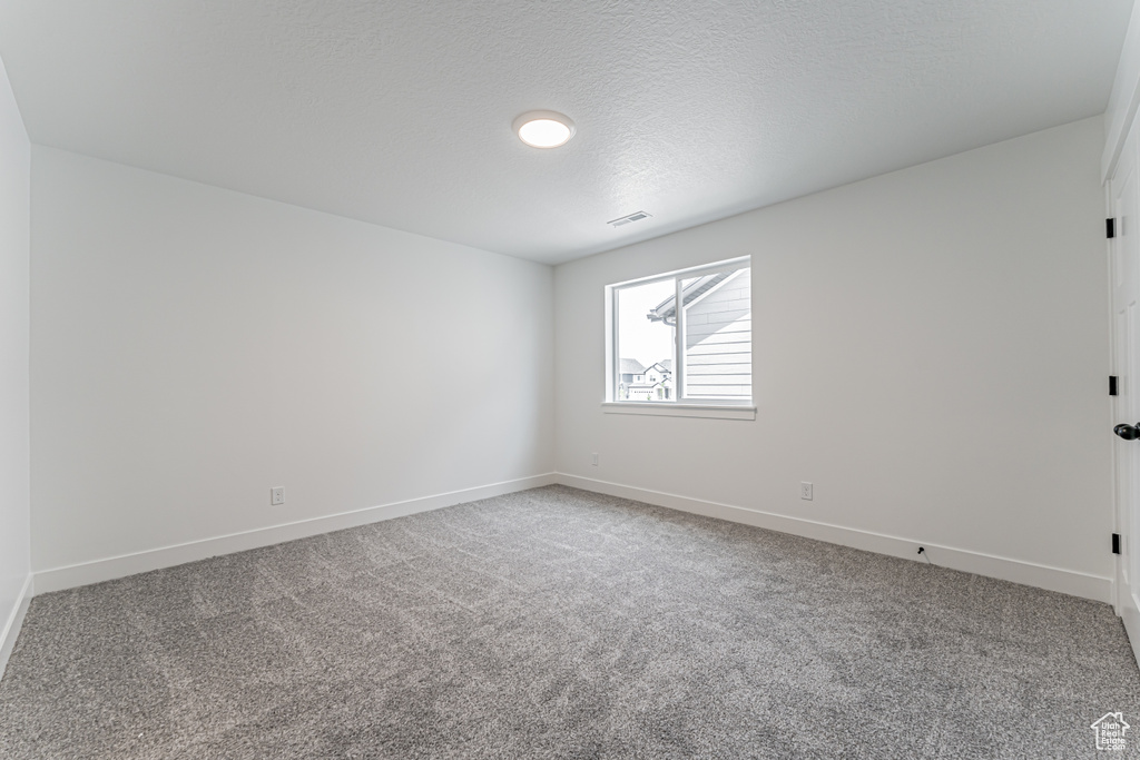 Carpeted empty room with baseboards and a textured ceiling