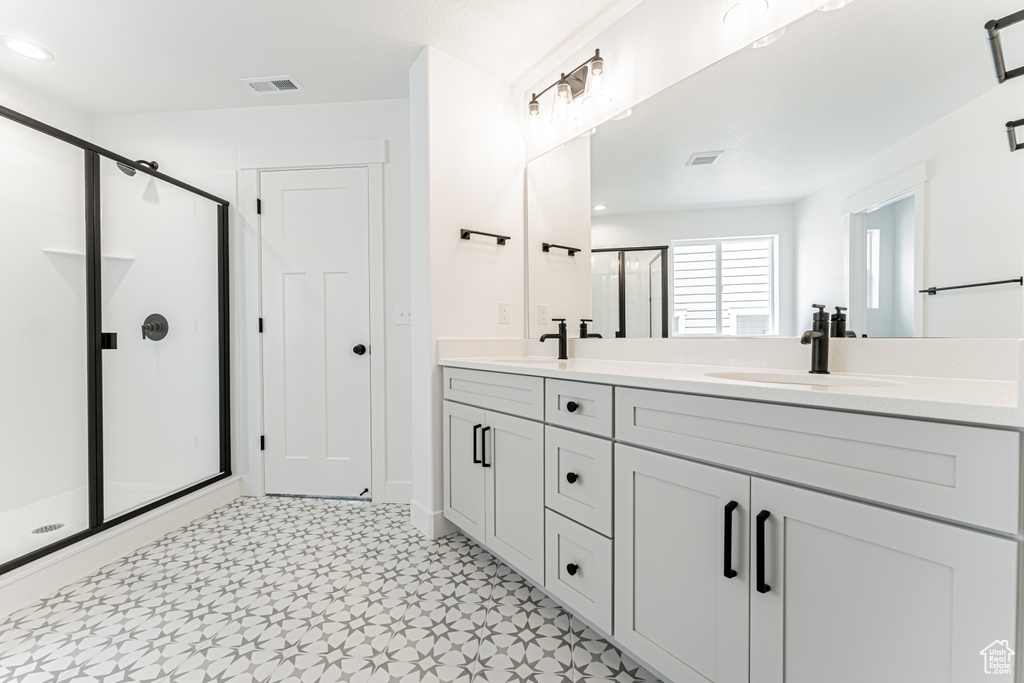 Full bathroom with double vanity, a shower stall, tile patterned floors, and recessed lighting