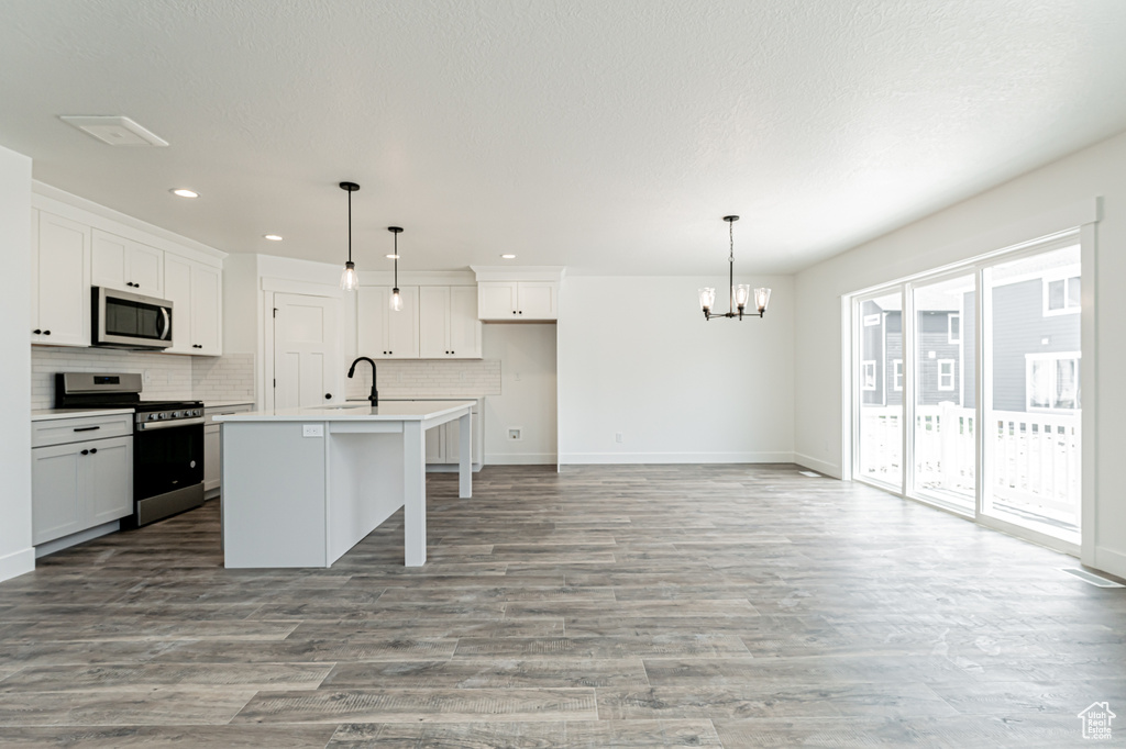 Kitchen featuring appliances with stainless steel finishes, a chandelier, recessed lighting, baseboards, and tasteful backsplash