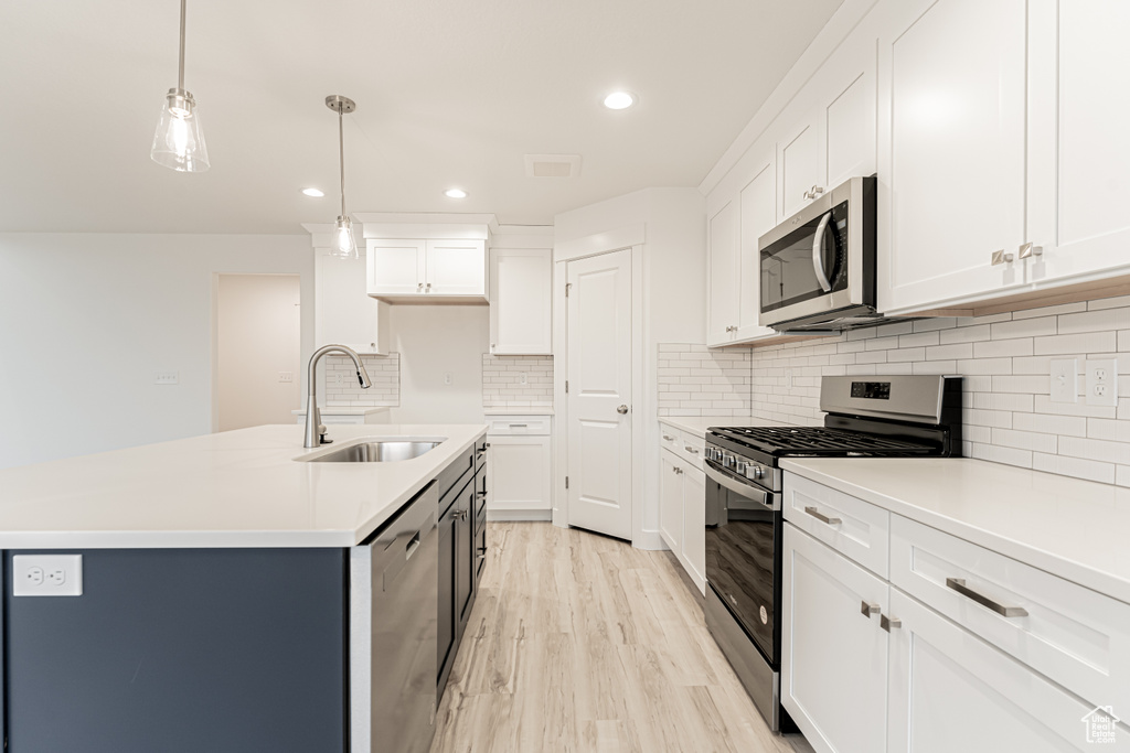 Kitchen featuring light wood-type flooring, visible vents, a sink, appliances with stainless steel finishes, and light countertops