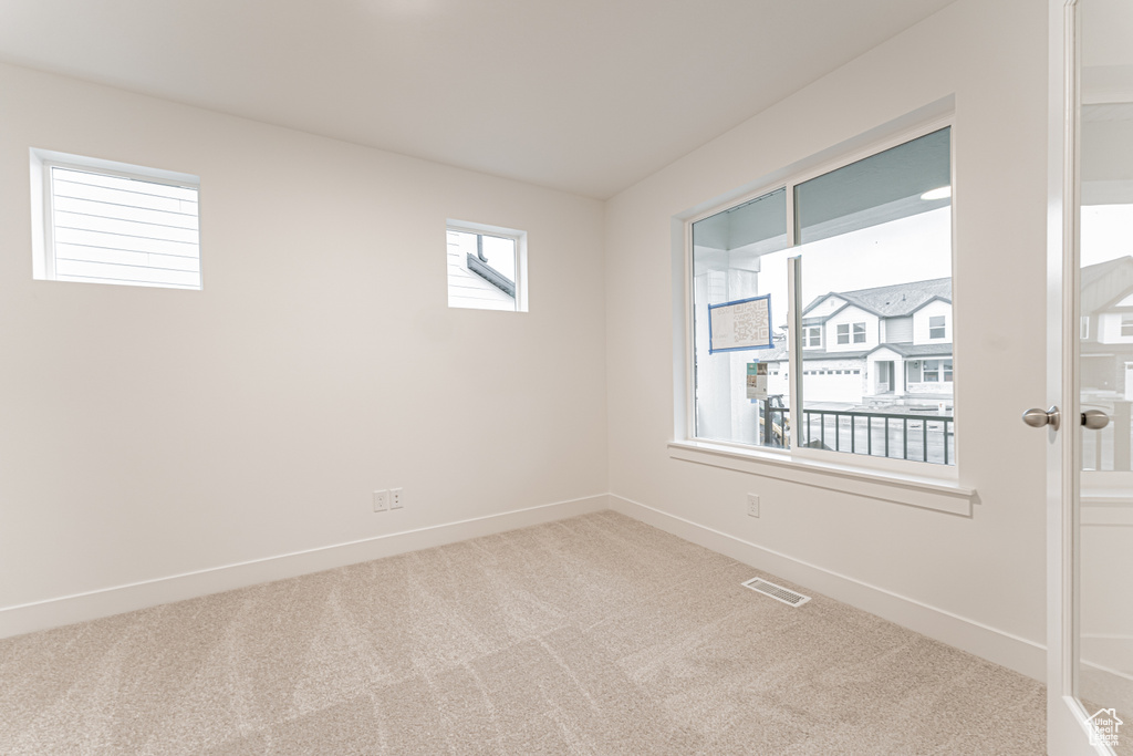 Carpeted empty room featuring visible vents and baseboards