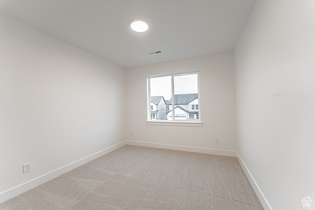 Empty room featuring light carpet, visible vents, and baseboards
