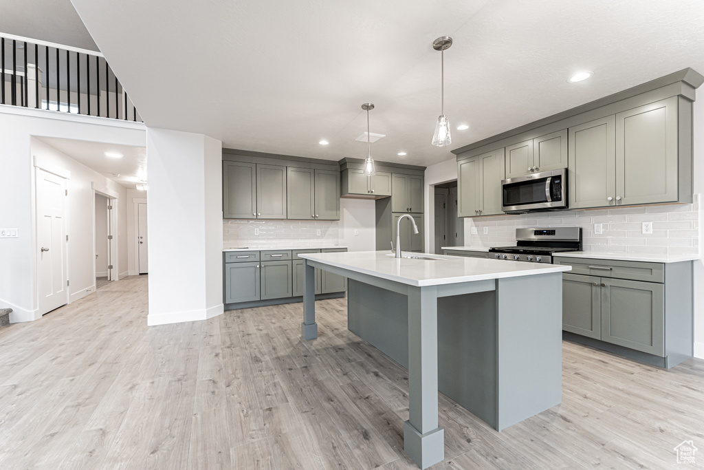 Kitchen featuring gray cabinetry, stainless steel appliances, light wood-type flooring, and a sink