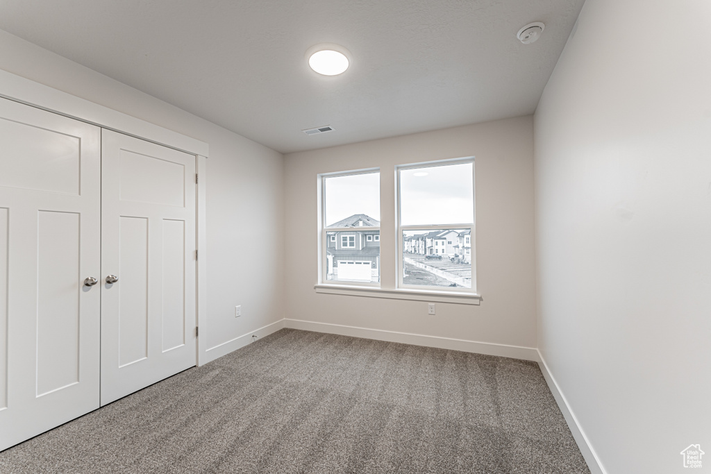 Spare room featuring visible vents, carpet, and baseboards