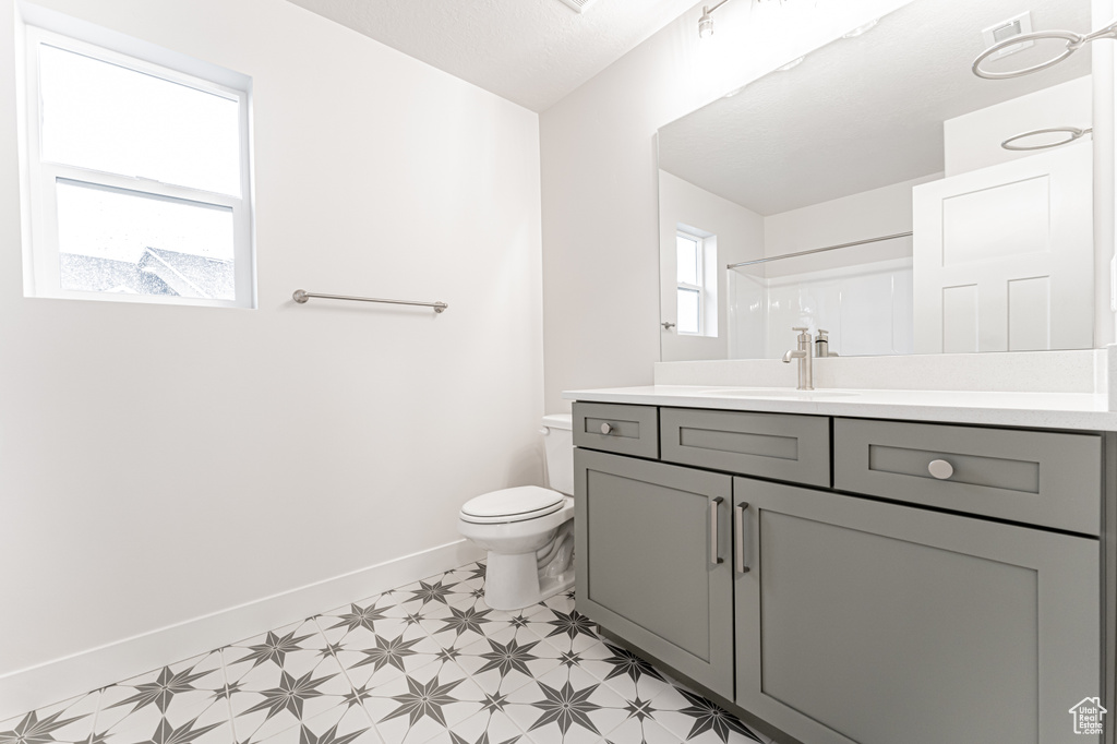 Full bath with tile patterned floors, baseboards, toilet, and vanity