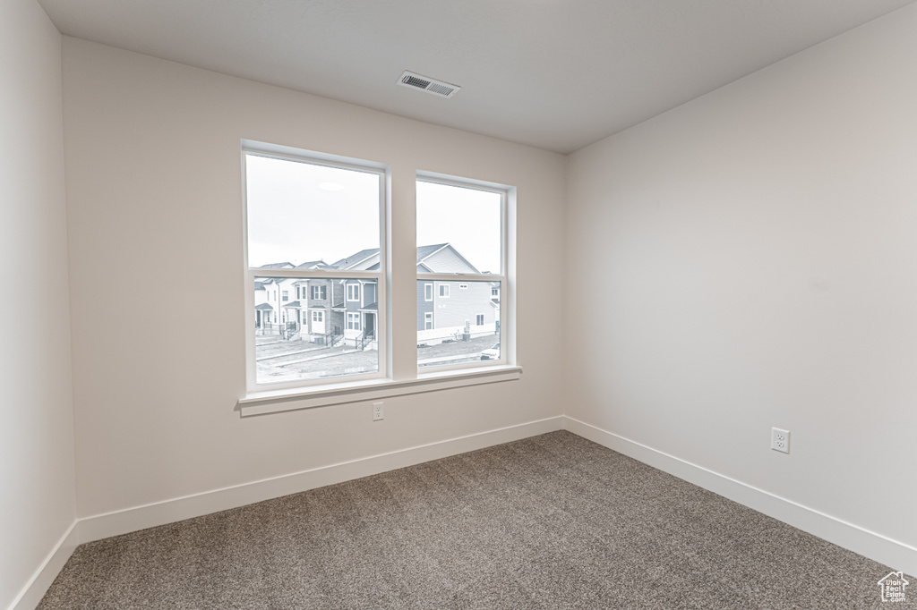 Carpeted empty room with visible vents and baseboards