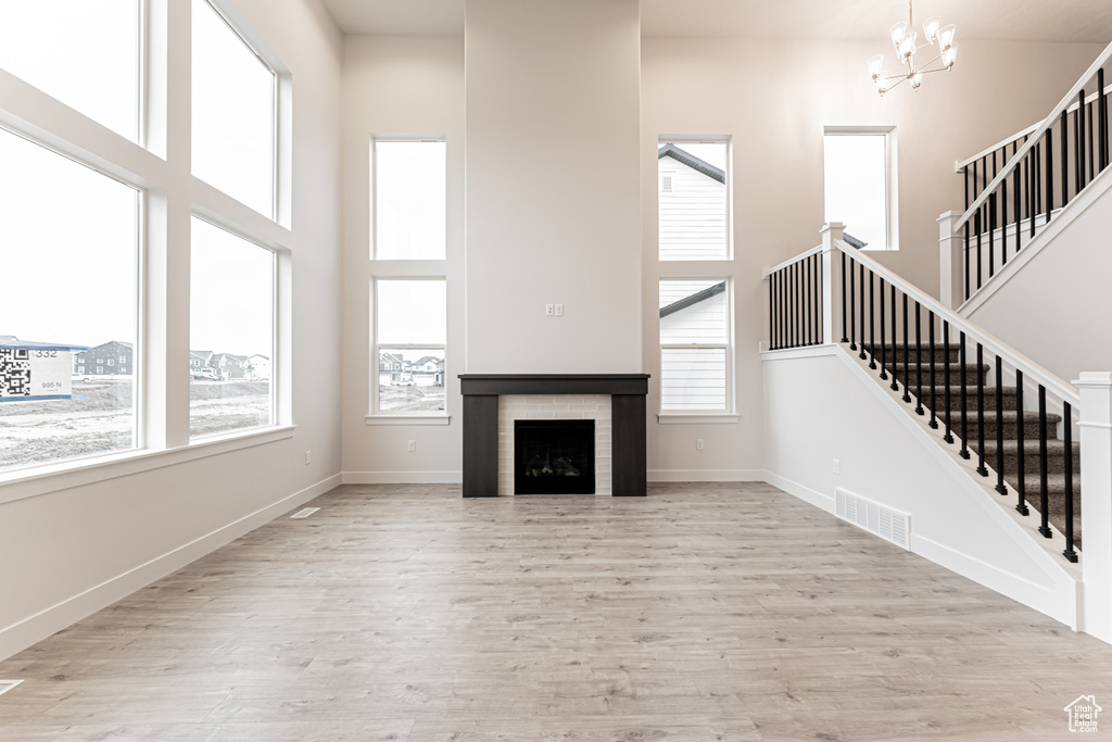 Unfurnished living room with visible vents, a high ceiling, wood finished floors, and stairs
