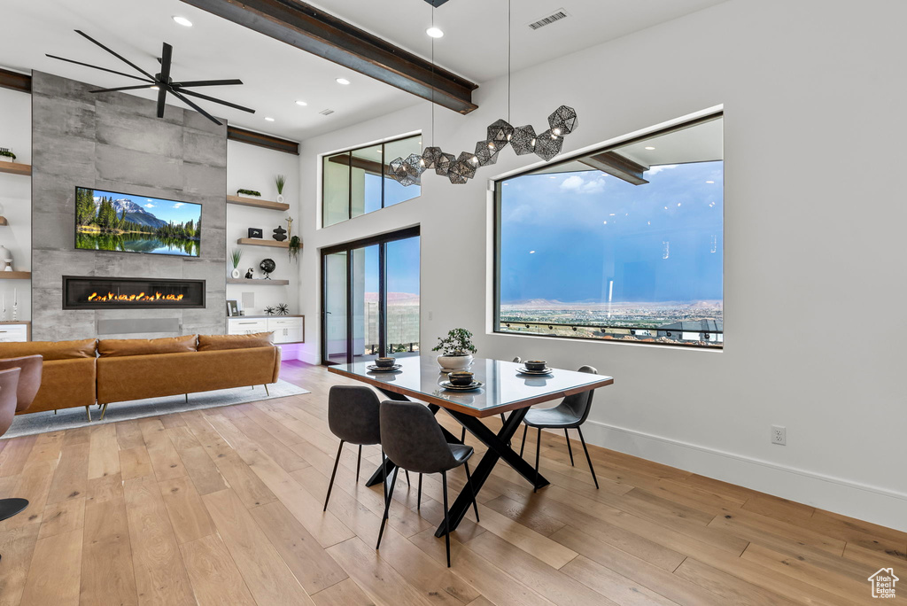 Dining area with ceiling fan, light wood-type flooring, and a tiled fireplace