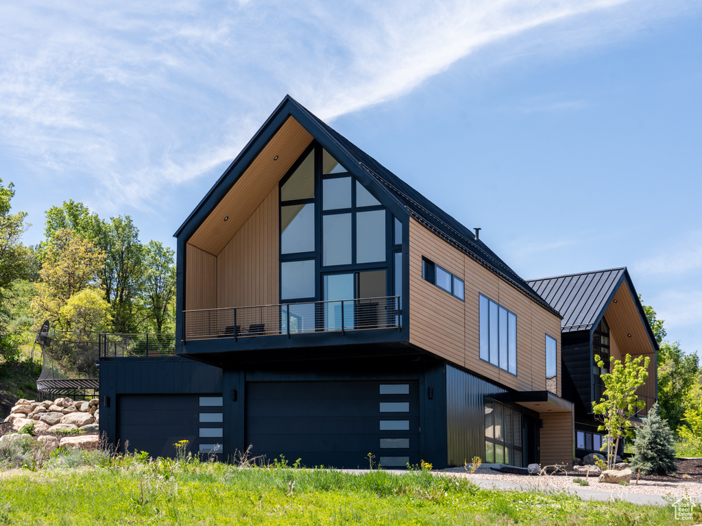View of front of property with a balcony, a garage, metal roof, and a standing seam roof