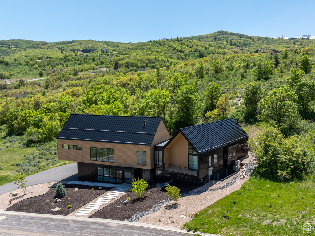Aerial view of property and surrounding area with a forest and mountains