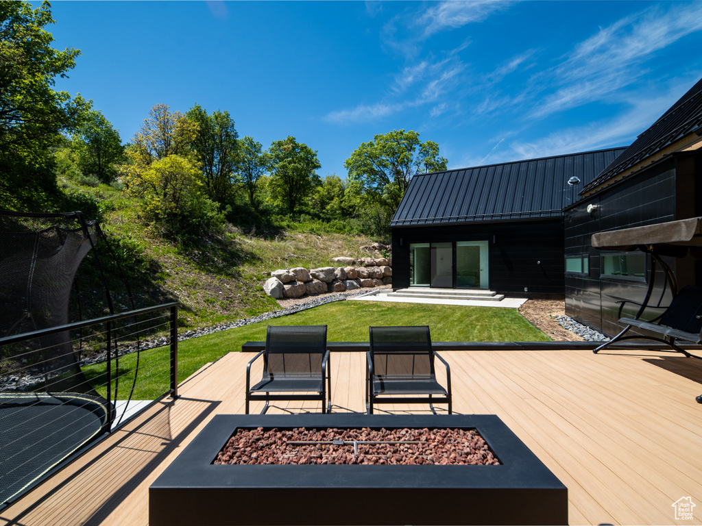 Wooden terrace with a fire pit and a lawn